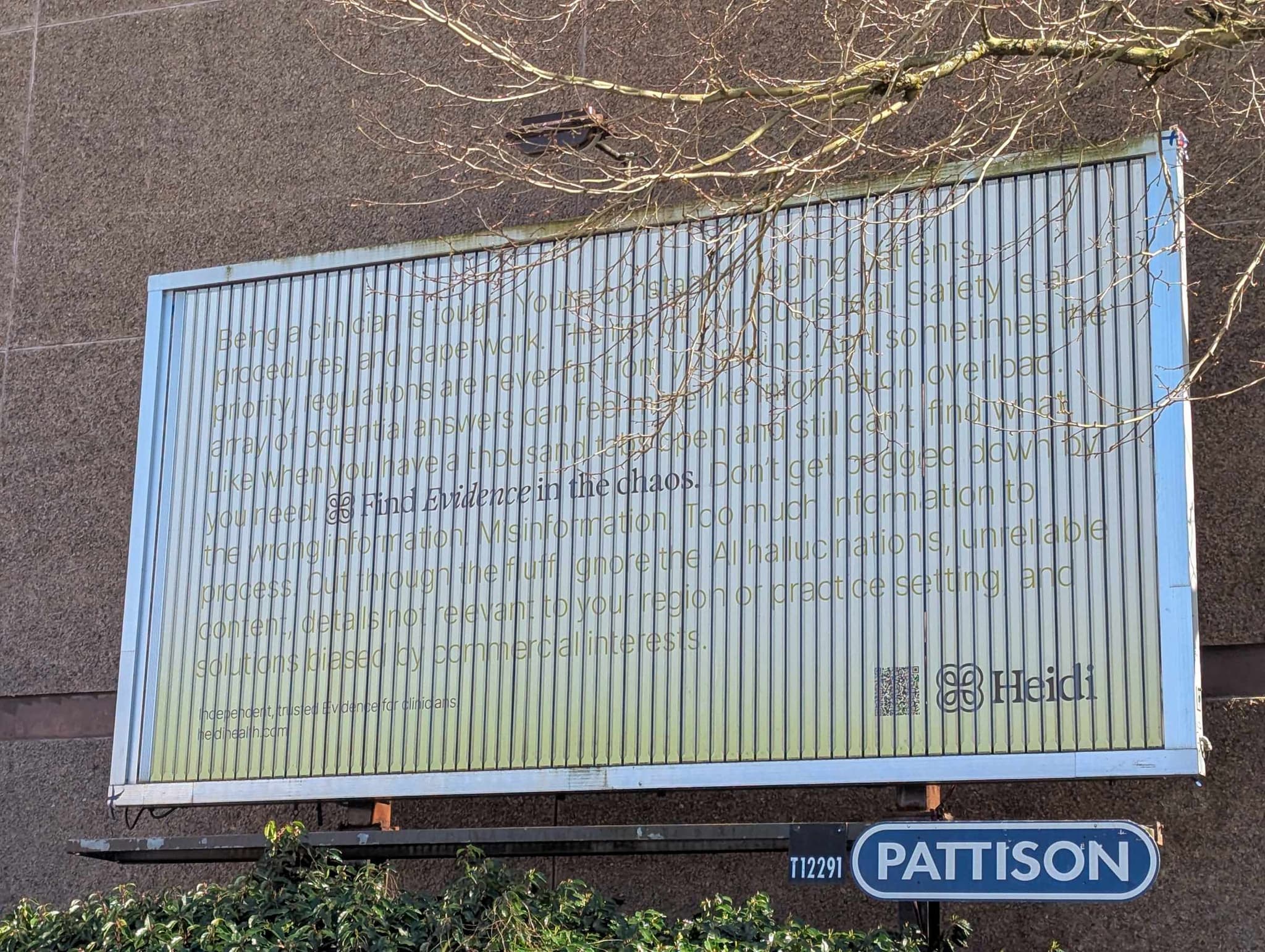 Pattison billboard showing a Heidi ad behind bare tree branches