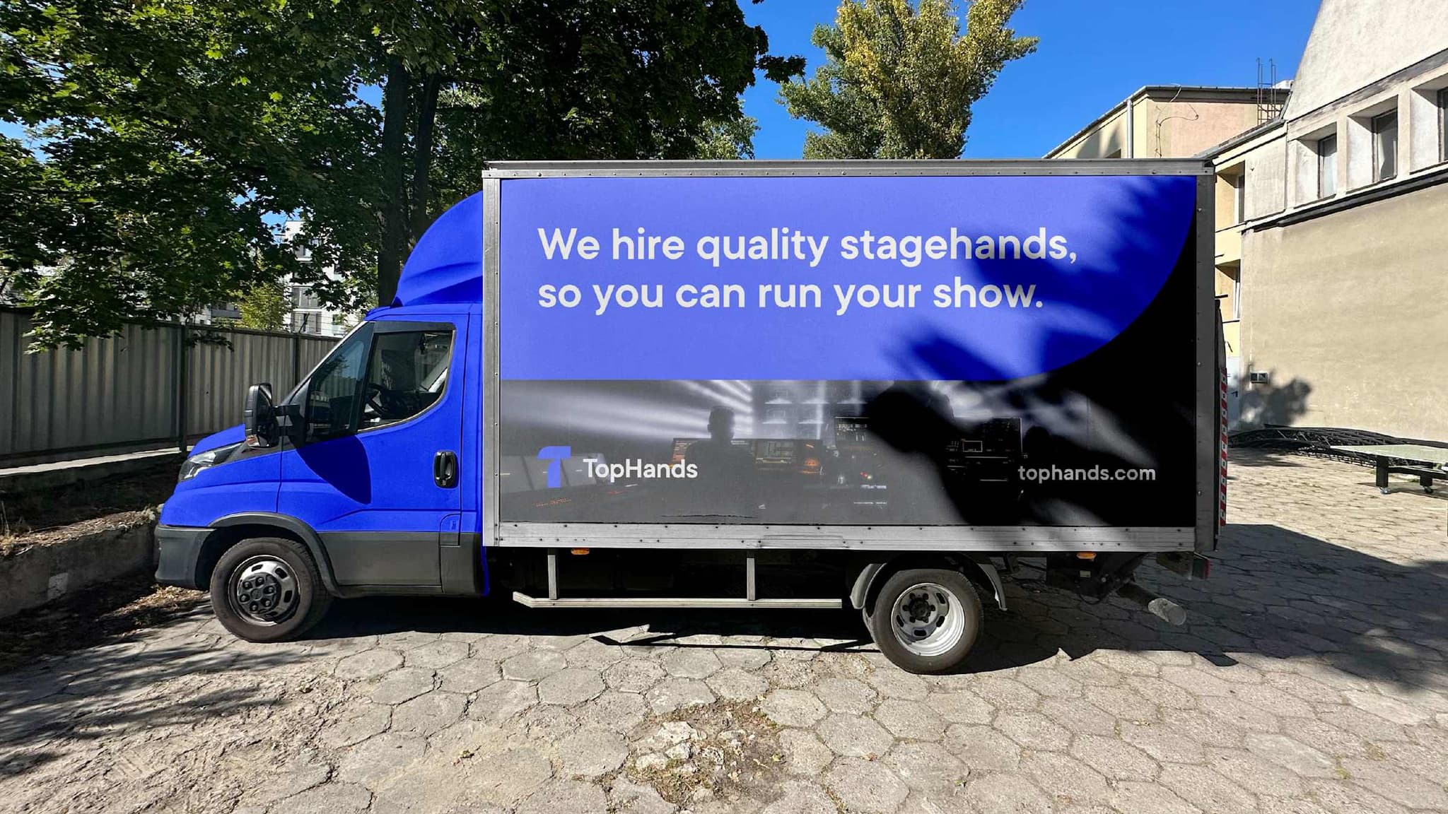 Box truck wrapped with a TopHands advertisement reading “We hire quality stagehands, so you can run your show.”